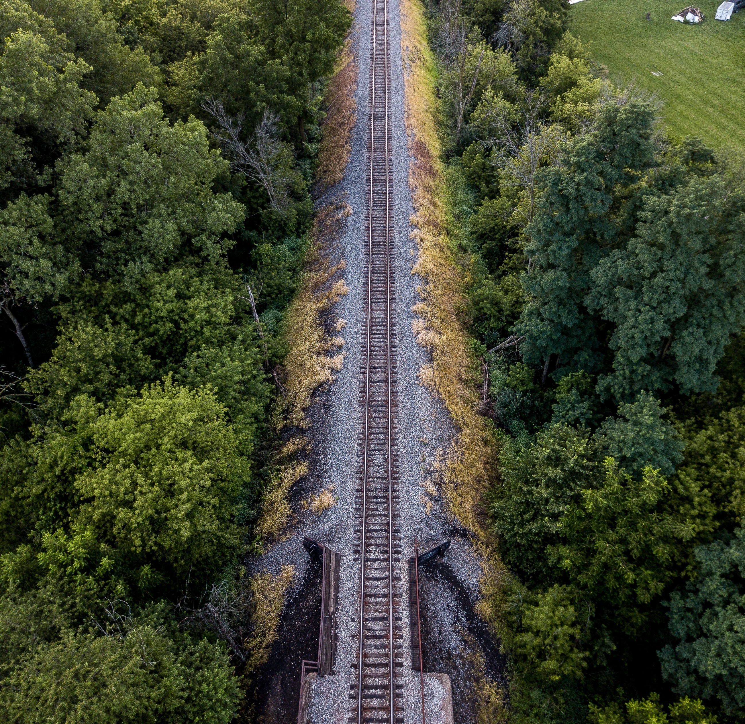 A railway cuts a precise line through green fields in an original Holley Creative aerial photograph