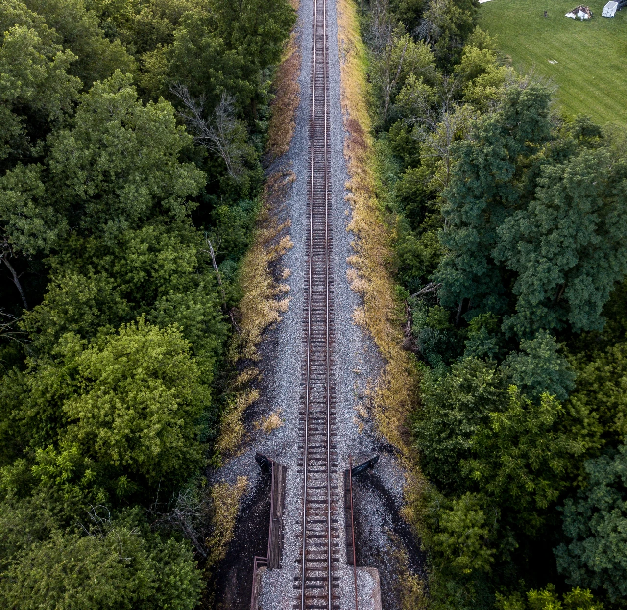 A railway cuts a precise line through green fields in an original Holley Creative aerial photograph